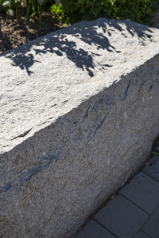 Solbelyst blockstensmur i grå granit.
