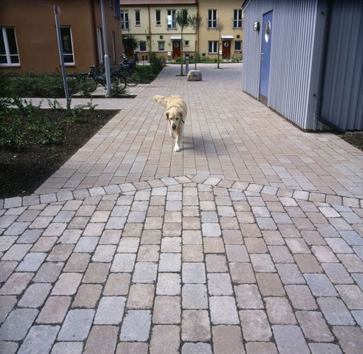 Miljöbild av S:t Eriks marksten Rustik i färgen naturgrå med inslag av stenar i terra och sand.