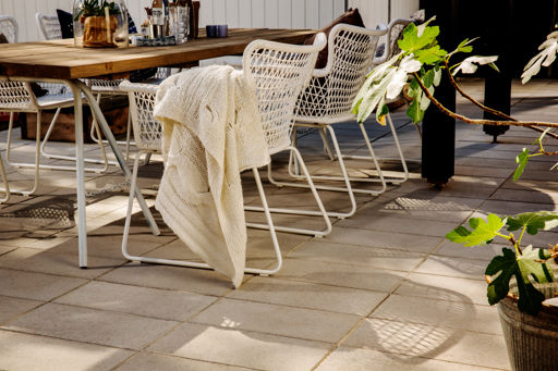 Klassikplattan lagd i trädgårdsmiljö med utemöbler.