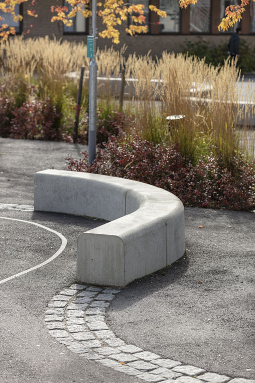 Outline-bänkar bildar en ringlande orm på en med gul vass och buskar