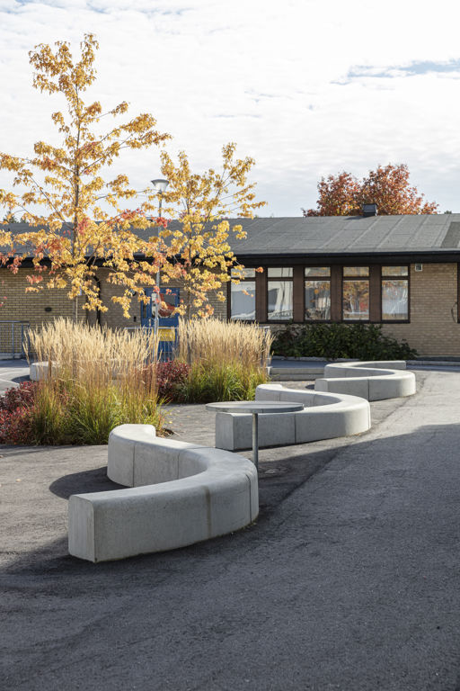 Flera Outline-bänkar bildar en ringlande orm på en skolgård