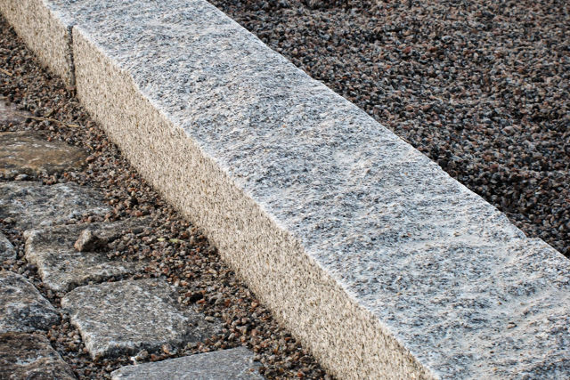 Granitkantsten av typen RFV monterad mellan gångyta och planteringsyta;i kombination med smågatsten och grus.