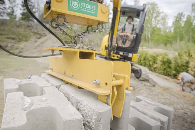 Montering av Verticamur med hjälp av en liten grävmaskin och ett hydrauliskt lyftverktyg för Verticamur.